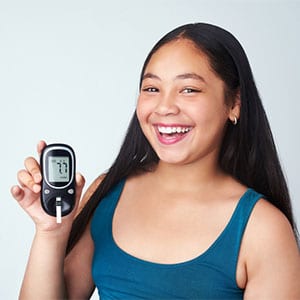 smiling girl holding blood sugar monitor