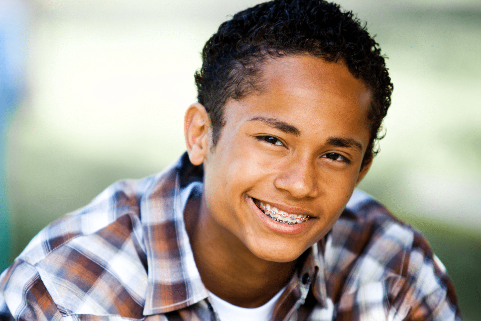 Smiling teenage boy with short curly hair wearing metal braces